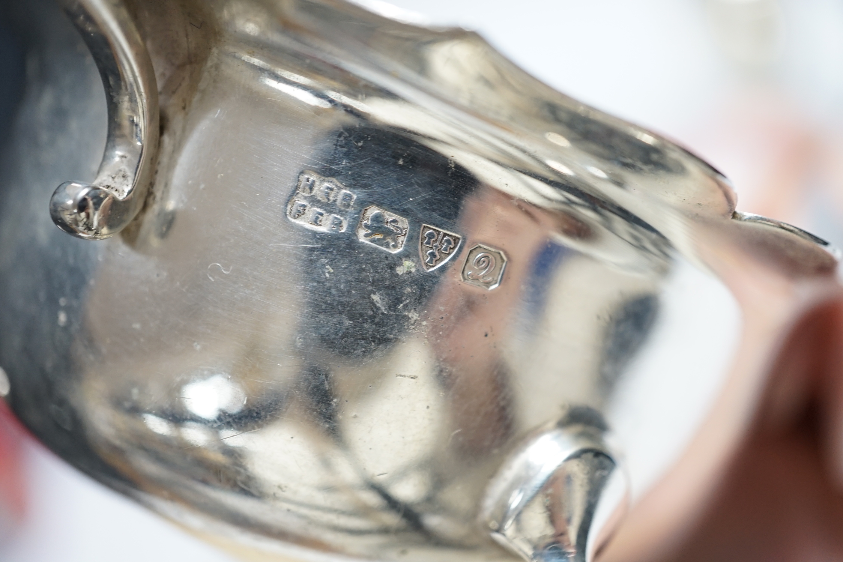 Four pieces of George V silver:- a sauceboat, a mustard pot, a vase and a cup.